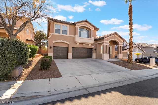 mediterranean / spanish-style home with a tile roof, driveway, an attached garage, and stucco siding