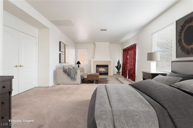 bedroom with light carpet, a large fireplace, and visible vents