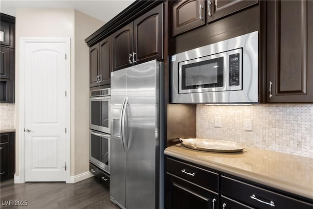 kitchen featuring light countertops, decorative backsplash, appliances with stainless steel finishes, dark wood-type flooring, and dark brown cabinets