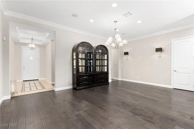 unfurnished dining area featuring a notable chandelier, visible vents, ornamental molding, wood finished floors, and baseboards