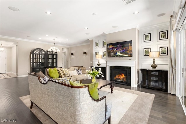 living area featuring a chandelier, wood finished floors, a fireplace with flush hearth, and crown molding