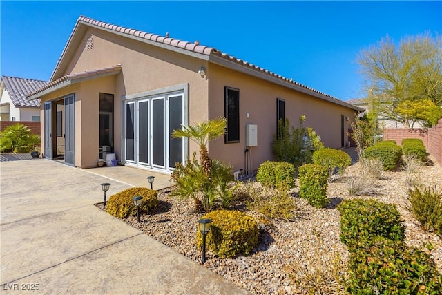 view of home's exterior featuring a patio, a tile roof, fence, and stucco siding