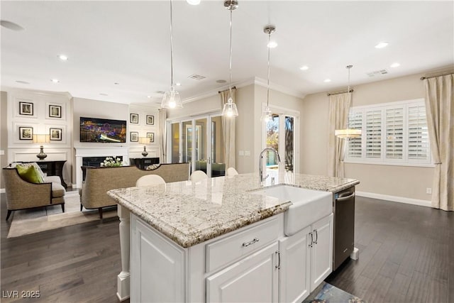 kitchen featuring dark wood-style floors, light stone counters, a center island with sink, stainless steel dishwasher, and a sink