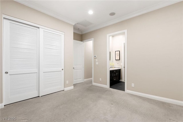 unfurnished bedroom featuring ensuite bathroom, carpet floors, baseboards, a closet, and crown molding