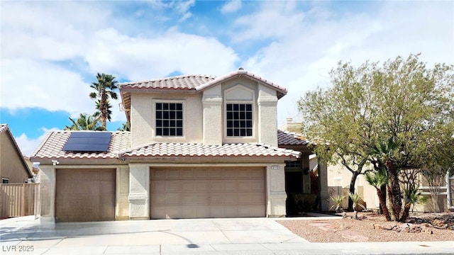 mediterranean / spanish-style home featuring an attached garage, solar panels, a tiled roof, driveway, and stucco siding