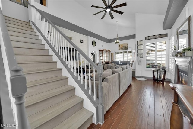 living area with dark wood finished floors, stairway, a healthy amount of sunlight, and a ceiling fan