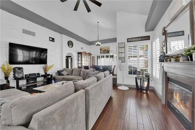 living room featuring visible vents, high vaulted ceiling, a ceiling fan, dark wood-style floors, and a fireplace