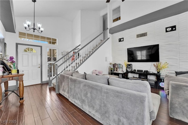 living room with visible vents, a chandelier, stairs, high vaulted ceiling, and dark wood-style flooring