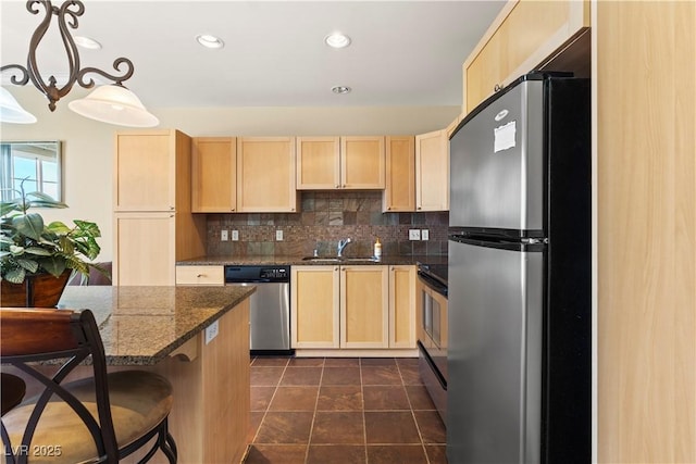 kitchen with a sink, stainless steel appliances, light brown cabinetry, a kitchen bar, and backsplash