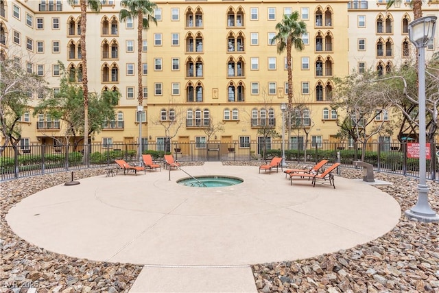 view of swimming pool featuring a community hot tub, a patio, and fence