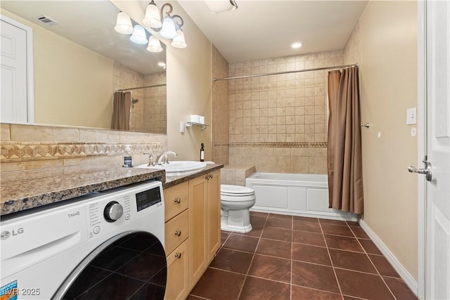 bathroom with washer / dryer, toilet, tile patterned floors, shower / bath combo with shower curtain, and vanity