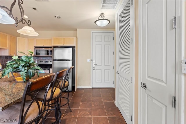 kitchen with visible vents, decorative backsplash, appliances with stainless steel finishes, light brown cabinetry, and dark tile patterned floors