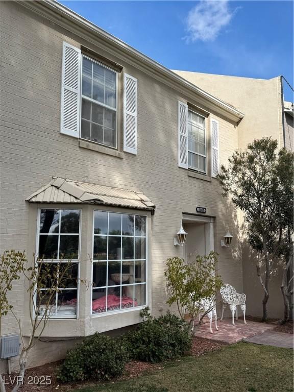 view of side of property featuring brick siding and a patio area