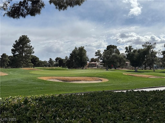 view of property's community featuring view of golf course and a lawn