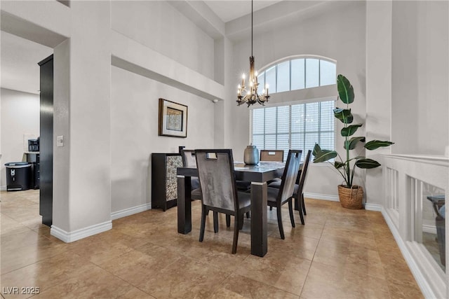 dining space featuring tile patterned floors, baseboards, and an inviting chandelier