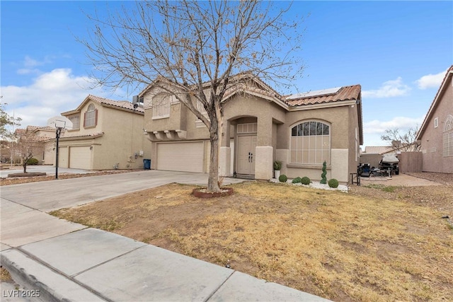 mediterranean / spanish-style home with solar panels, driveway, an attached garage, and stucco siding