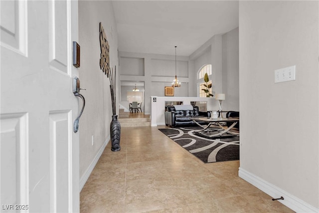 foyer entrance with a chandelier and baseboards