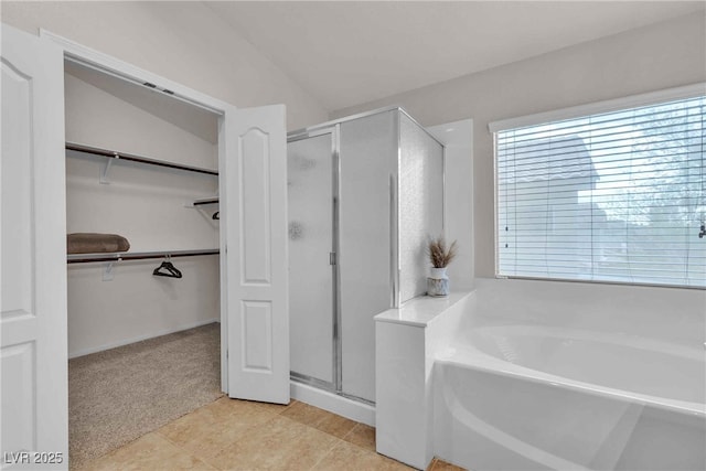 bathroom with a stall shower, a walk in closet, and a bath