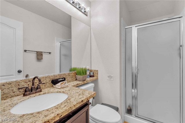 bathroom with vanity, a shower stall, and toilet