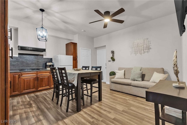 dining space with wood finished floors and ceiling fan with notable chandelier