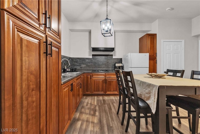 kitchen featuring a breakfast bar, gas stovetop, a sink, freestanding refrigerator, and brown cabinets