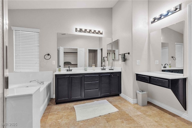 bathroom featuring a garden tub, double vanity, and a sink