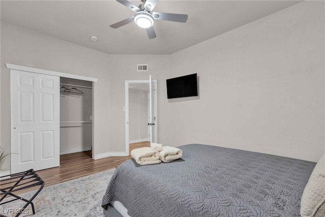 bedroom with a closet, visible vents, ceiling fan, wood finished floors, and baseboards