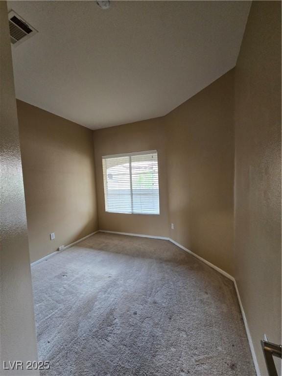 spare room featuring carpet flooring, visible vents, and baseboards