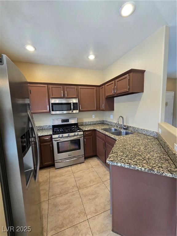 kitchen featuring recessed lighting, appliances with stainless steel finishes, light tile patterned flooring, a sink, and dark stone countertops