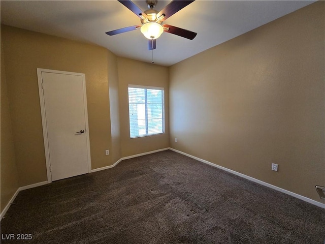 empty room with baseboards, dark carpet, and a ceiling fan