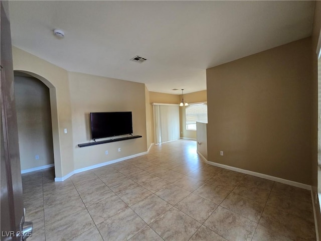 unfurnished living room with baseboards, visible vents, arched walkways, and light tile patterned flooring