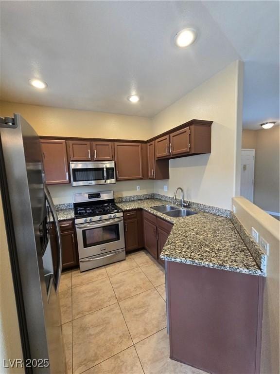 kitchen featuring dark stone countertops, appliances with stainless steel finishes, a sink, and recessed lighting