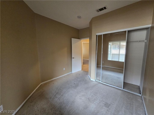 unfurnished bedroom with a closet, carpet flooring, visible vents, and baseboards