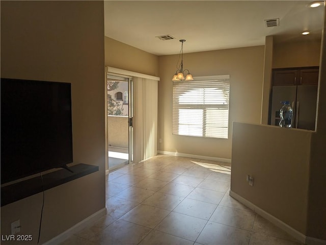 unfurnished dining area featuring visible vents, a notable chandelier, baseboards, and light tile patterned floors