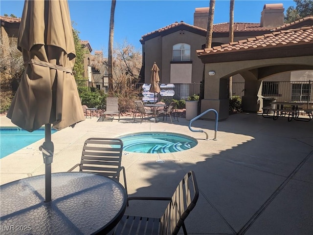 pool featuring outdoor dining area, a patio area, fence, and a hot tub