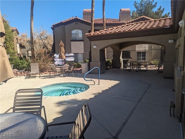 view of pool with a patio, outdoor dining space, fence, and a hot tub