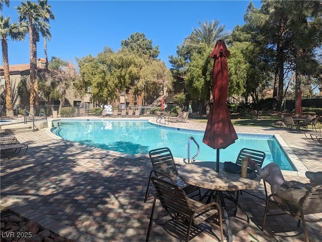 pool with a patio area and fence