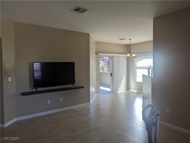 unfurnished living room with an inviting chandelier, baseboards, visible vents, and tile patterned flooring