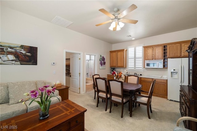 dining room featuring a ceiling fan, visible vents, and light colored carpet