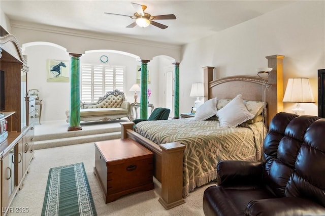 bedroom with a ceiling fan, arched walkways, light colored carpet, and decorative columns