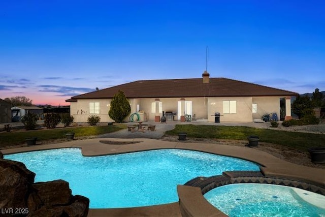 pool at dusk with a pool with connected hot tub and a patio