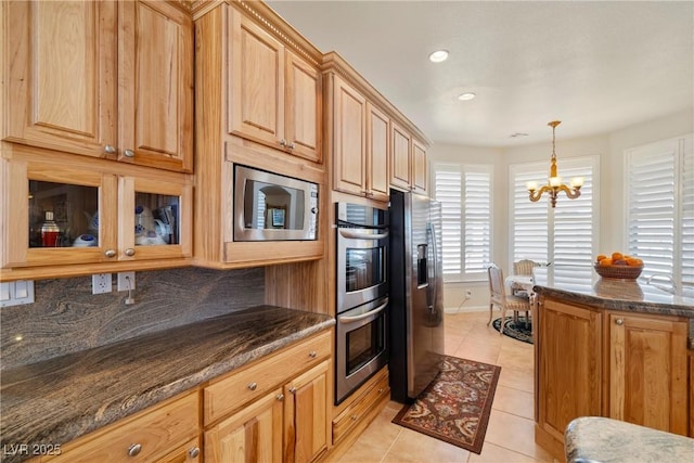 kitchen featuring light tile patterned floors, stainless steel appliances, tasteful backsplash, decorative light fixtures, and an inviting chandelier