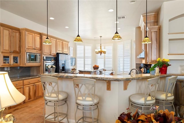 kitchen featuring light tile patterned floors, tasteful backsplash, visible vents, appliances with stainless steel finishes, and a breakfast bar