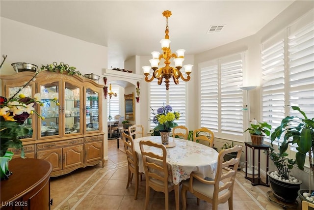 dining room featuring light tile patterned floors, visible vents, arched walkways, and a notable chandelier