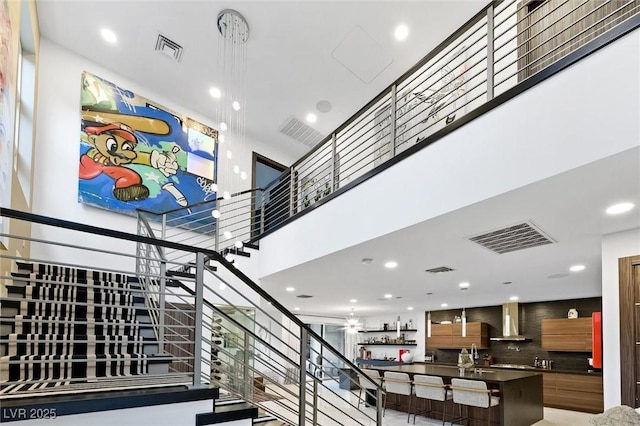 staircase with a high ceiling, visible vents, and recessed lighting