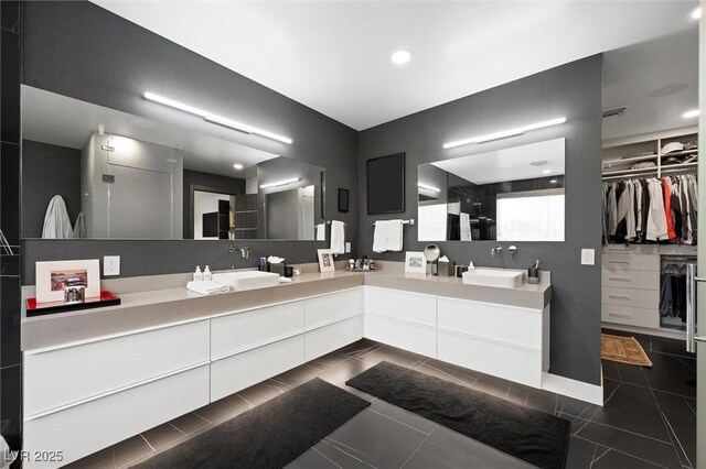 bathroom with double vanity, a spacious closet, a sink, and tile patterned floors