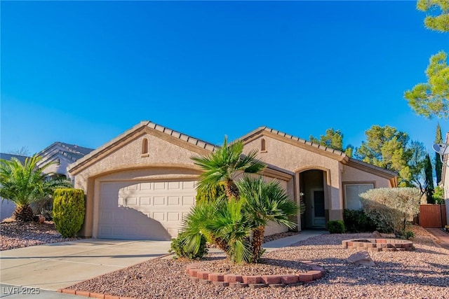 mediterranean / spanish home featuring an attached garage, a tile roof, concrete driveway, and stucco siding