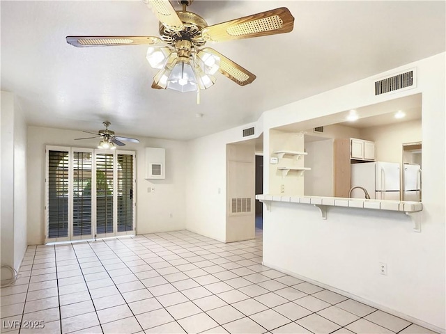 unfurnished room with light tile patterned floors, ceiling fan, and visible vents