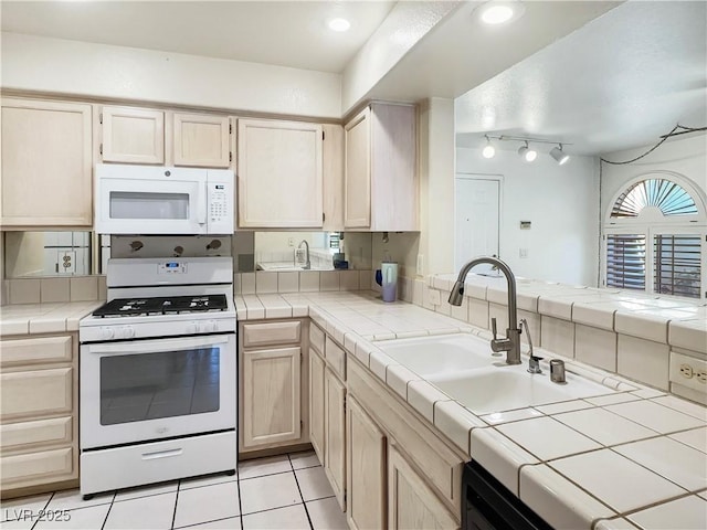 kitchen with white appliances, light tile patterned floors, tile counters, light brown cabinets, and a sink