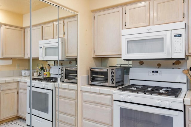 kitchen with tile countertops, white appliances, a toaster, and light brown cabinets